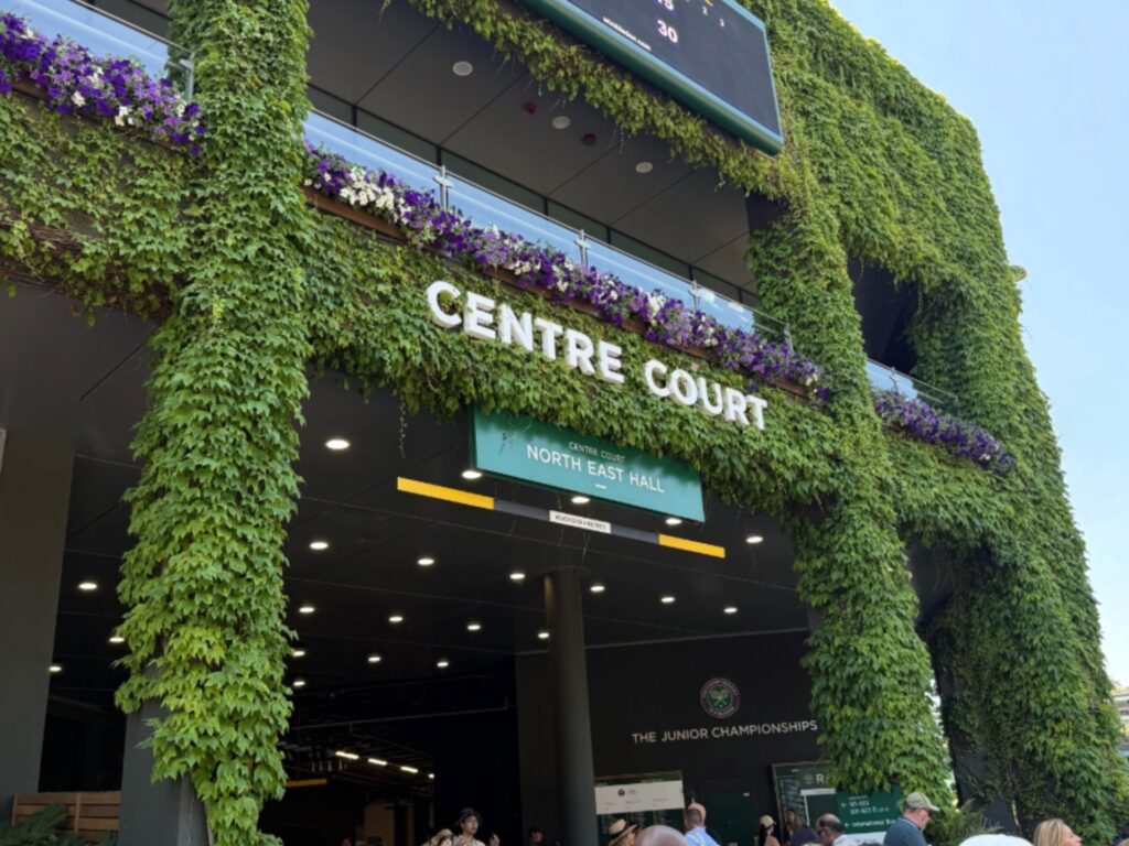 Entrance to a venue covered in ivy with white CENTRE COURT letters and a North East Hall sign