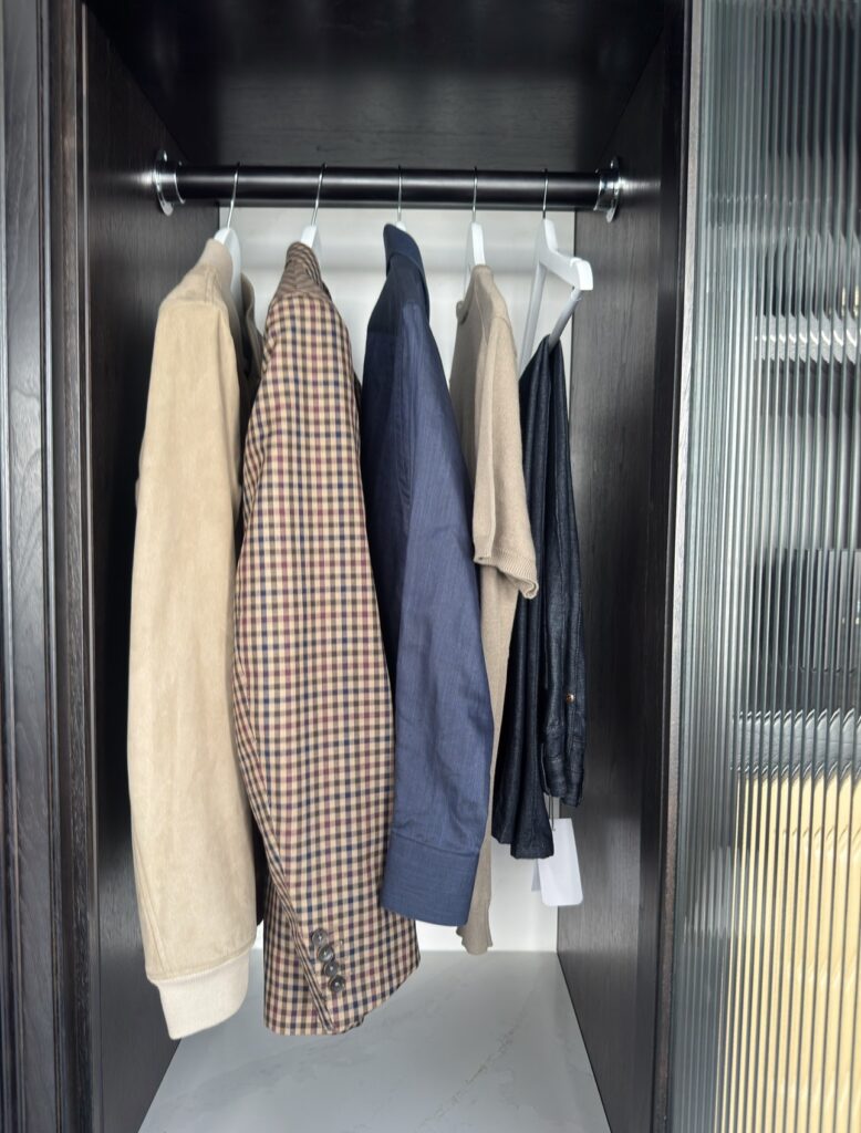 Coats and jackets hanging on a rod inside a dark wardrobe